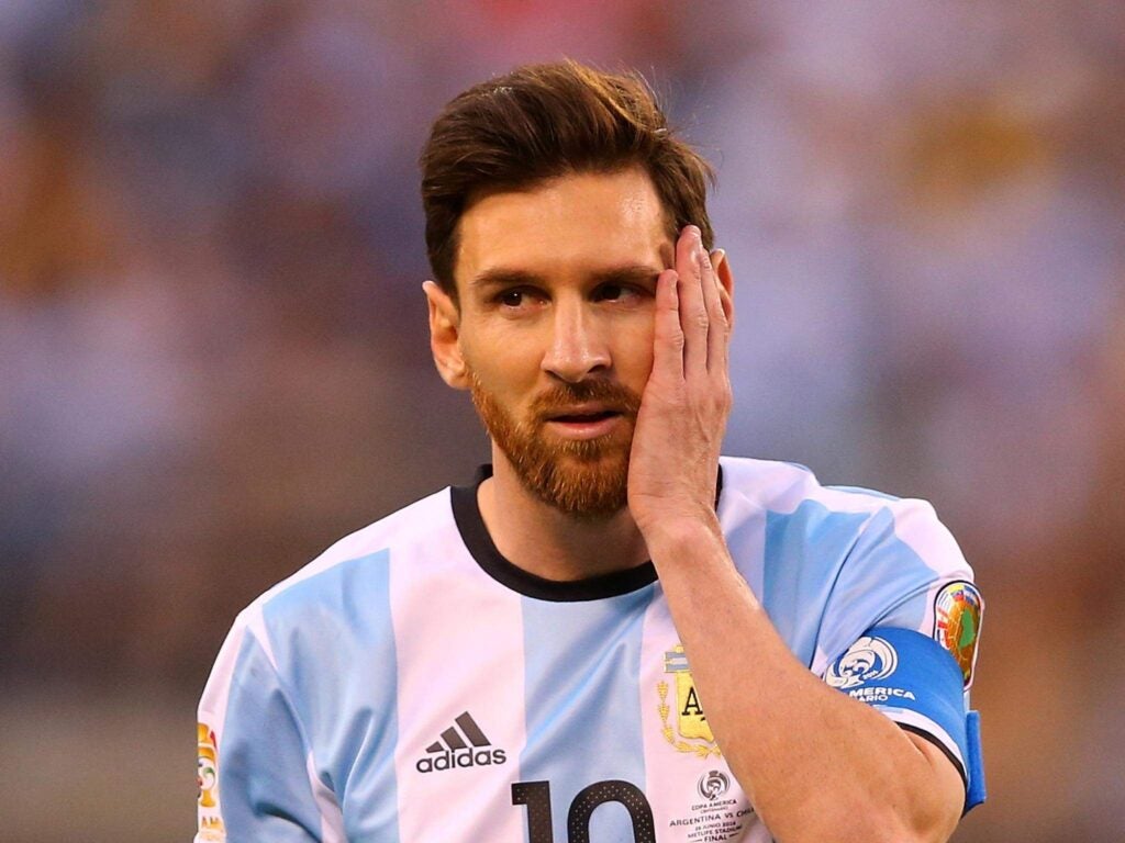 Lionel Messi in Argentina kit with left palm on left cheek 