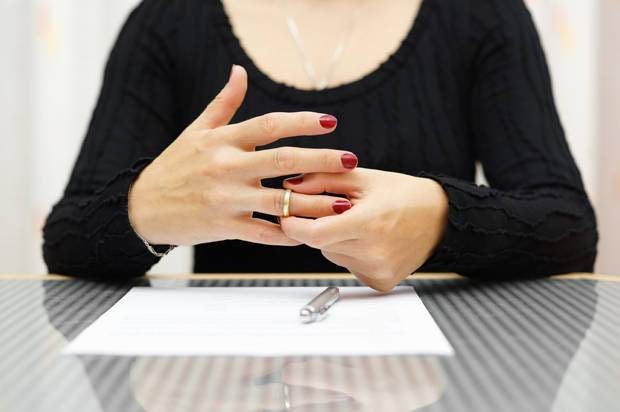 Woman taking her wedding ring off after signing divorce papers