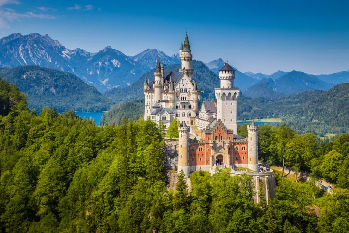 A Spring view of Neuschwanstein Castle, Germany, surrounded by high trees on a sunny day