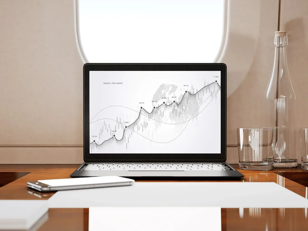 A laptop showing a financial investment graph aboard a private jet