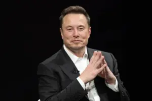 Elon Musk with his fingers together and slightly smiling