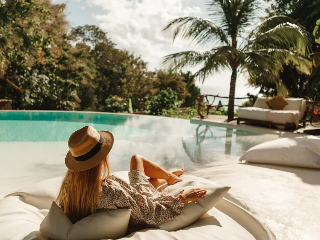 Woman reclining by a pool in a tropical location