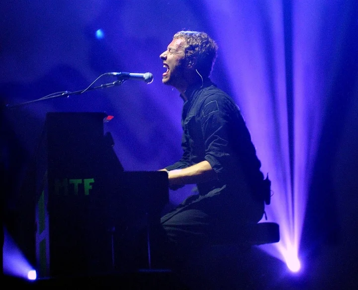 Chris Martin from Coldplay performing a show with blue light and a piano