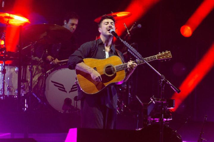 Marcus Mumford during a concert of Mumford & Sons playing the guitar and singing