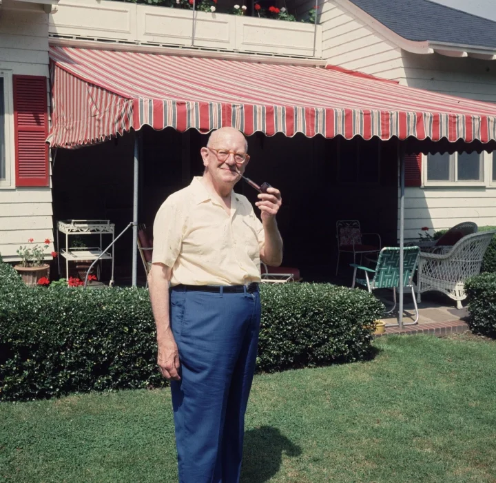 P G Wodehouse smoking a pipe on a sunny day.