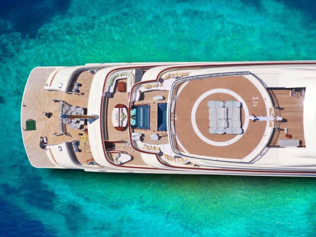 A drone shot of a yacht on beautiful green and blue sea water