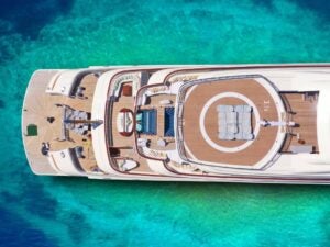 A drone shot of a yacht on beautiful green and blue sea water