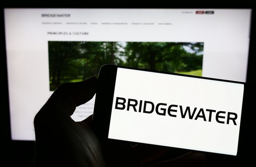 Stuttgart, Germany - 12-30-2022: Person holding mobile phone with logo of US investment company Bridgewater Associates LP on screen in front of web page. Focus on phone display. Unmodified photo.