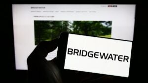 Stuttgart, Germany - 12-30-2022: Person holding mobile phone with logo of US investment company Bridgewater Associates LP on screen in front of web page. Focus on phone display. Unmodified photo.