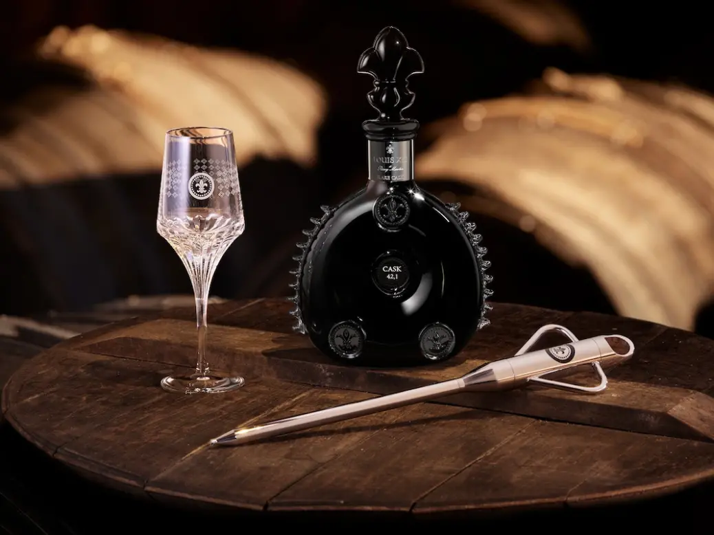 Bottle of Louis XIII Cognac on a table next to a glass and a letter opener