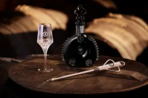 Bottle of Louis XIII Cognac on a table next to a glass and a letter opener