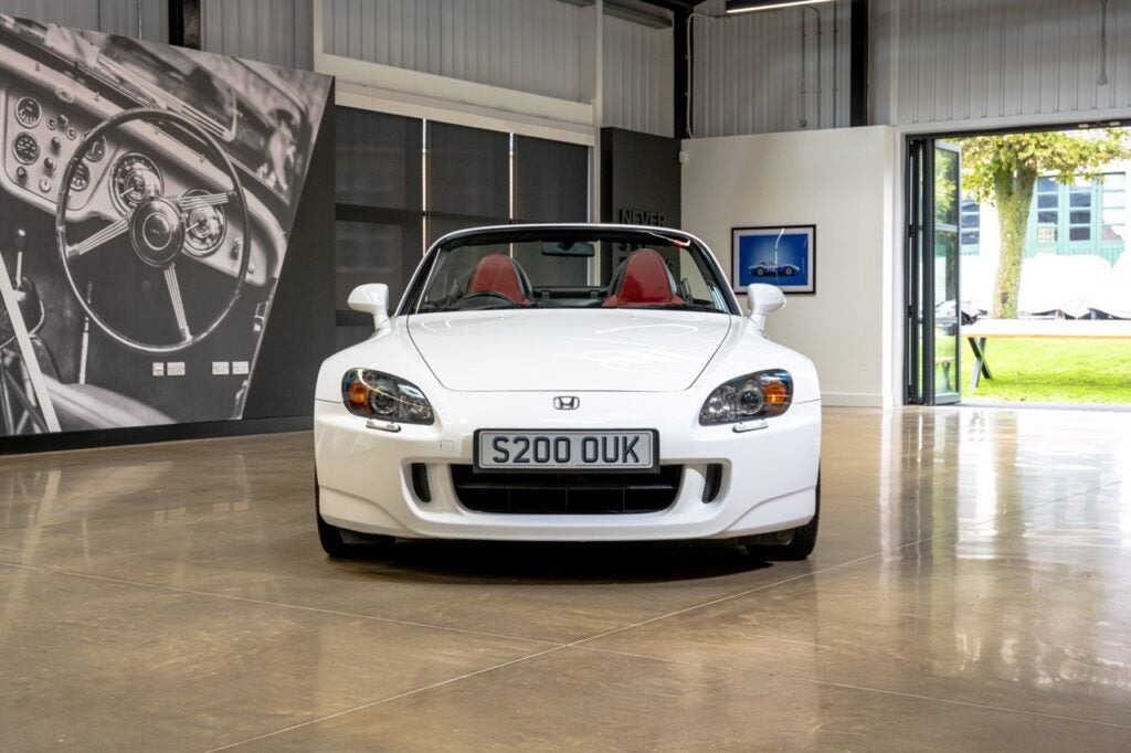 A white Honda S2000 in a showroom which has its double doors open