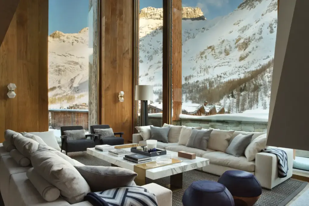 An upmarket living room with huge picture windows overlooking the mountains covered in snow