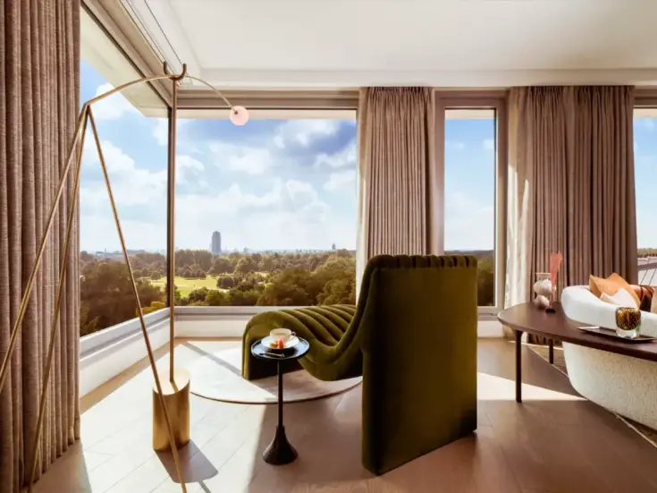 A room with an armchair overlooking Hyde Park through huge windows