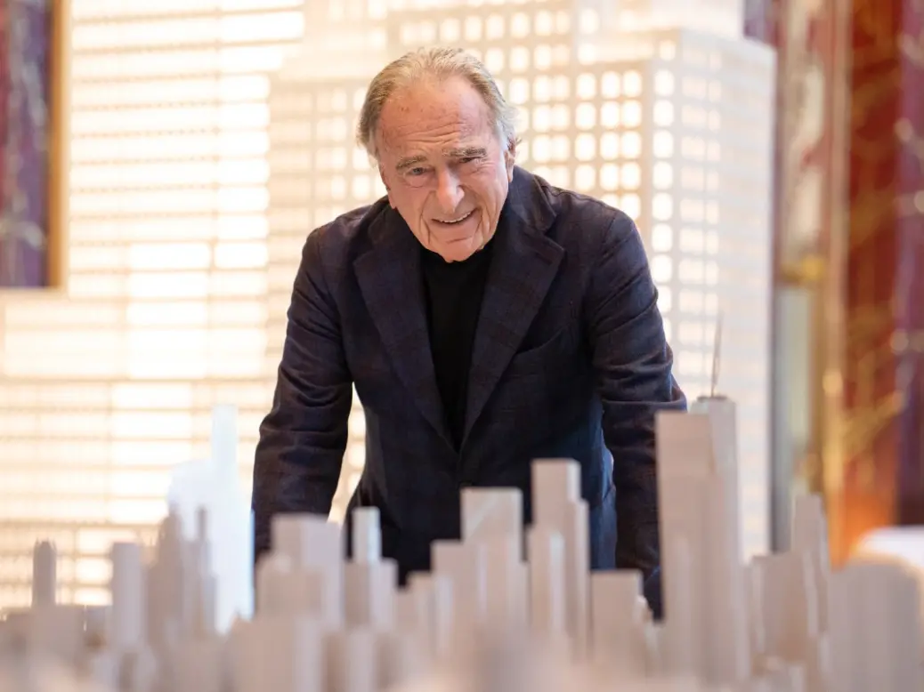 Harry Macklowe smiling and standing over a model of New York and One Wall Street
