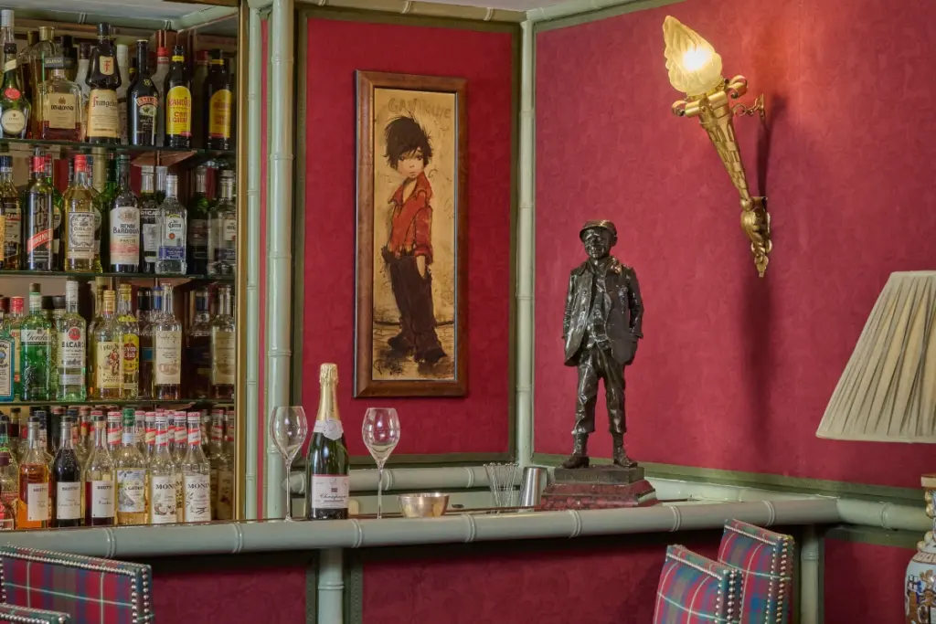 A painting of Gavroche from Les Misérables above the bar next to bottles of spirits