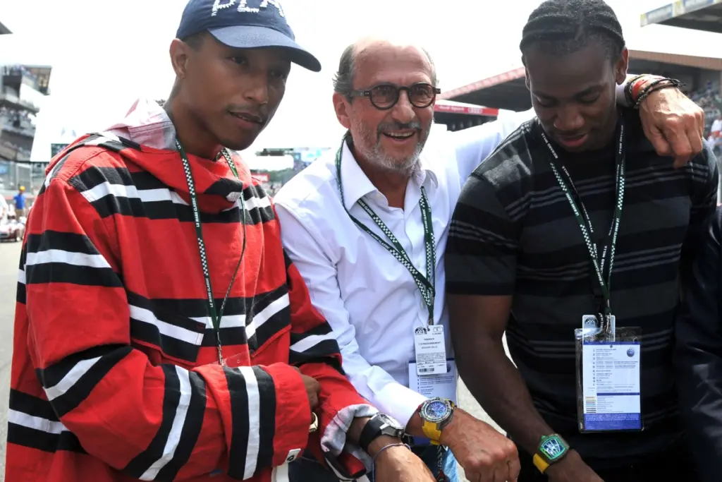 Founder Richard Mille (centre), musician Pharrell Williams (far left) and sprinter Yohan Blake pose with their watches at Le Mans in 2016